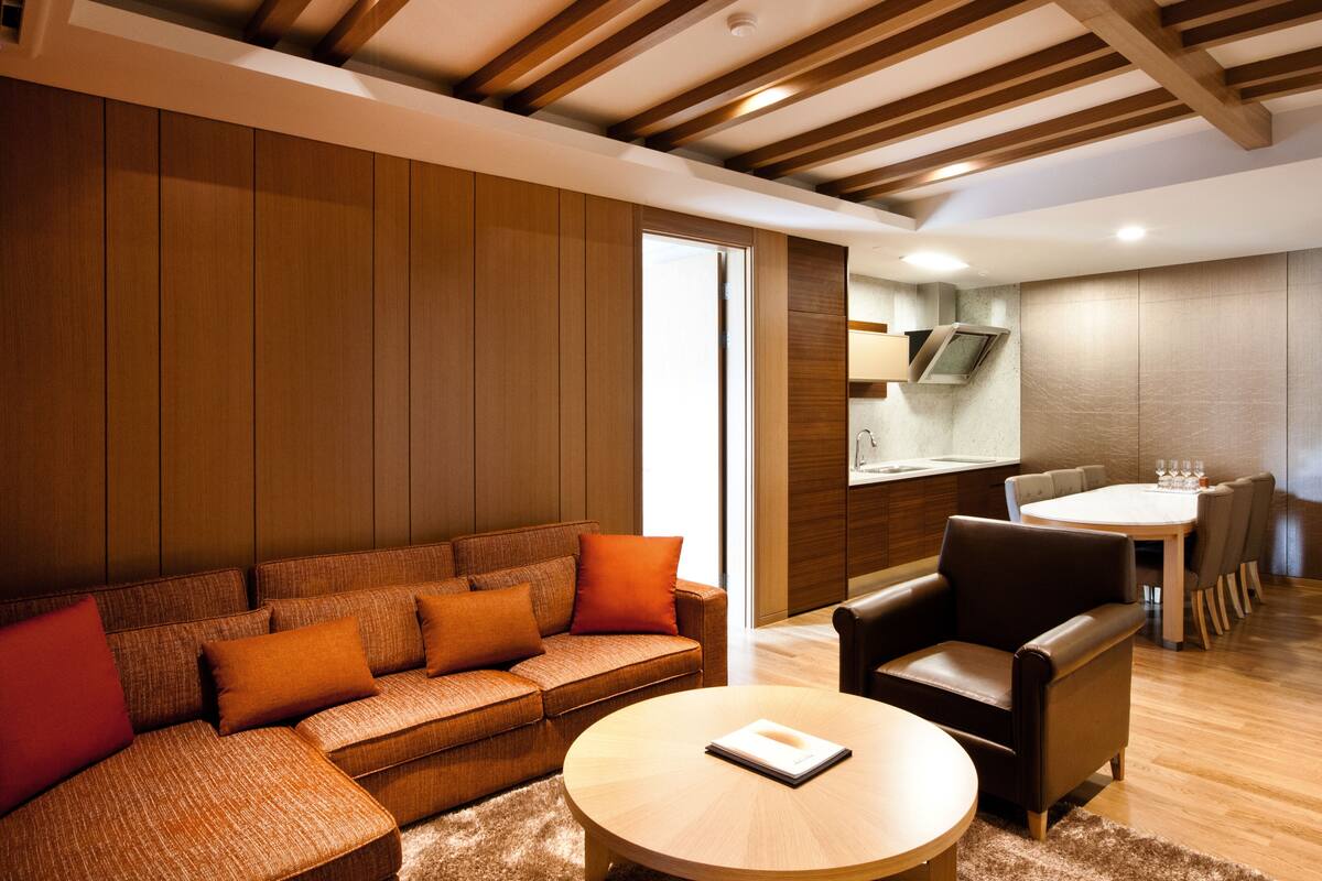 A modern living room with a sofa, coffee table, and a dining area with chairs and a table.