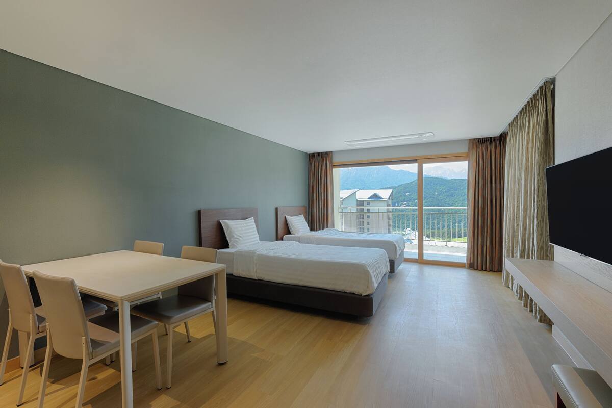 A hotel room with a large bed, a desk, and a TV.