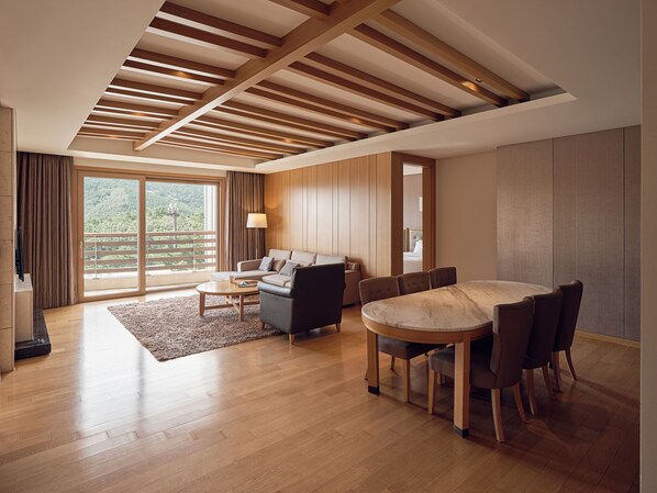 A modern living room with a wooden ceiling, a sofa set, a dining table with chairs, and a view through large sliding doors. - Del Pino (Goseong)