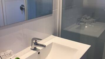 Ein modernes Badezimmer mit Waschbecken, Spiegel und Duschkabine.