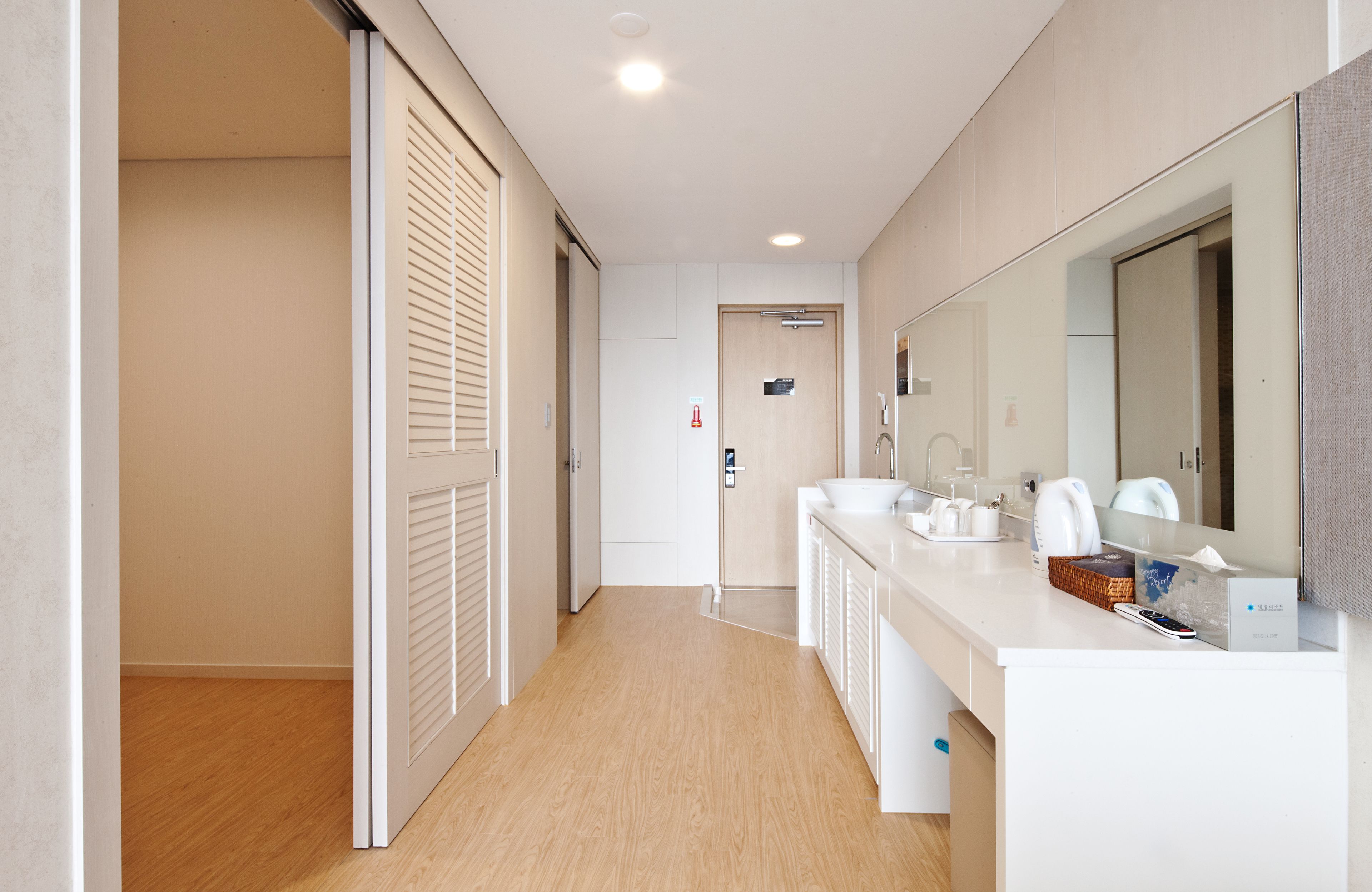 Un baño moderno con suelo de madera, sanitarios blancos y un espejo grande.