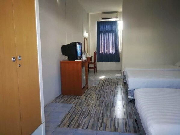 A hotel room with a bed, a desk with a television, a wardrobe, and a bathroom with a shower curtain.