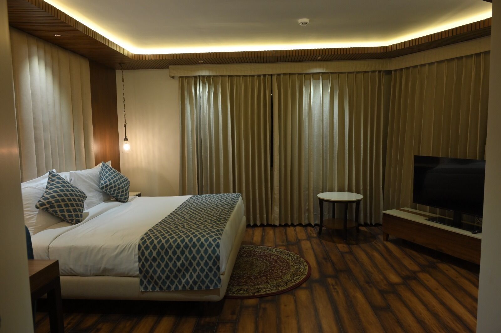 A hotel room with a large bed, a TV, and a small table.