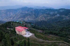 Un edificio con techo rojo, rodeado de un paisaje montañoso.