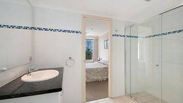 Une salle de bain équipée d’un lavabo, d’un miroir et d’une douche à parois de verre.