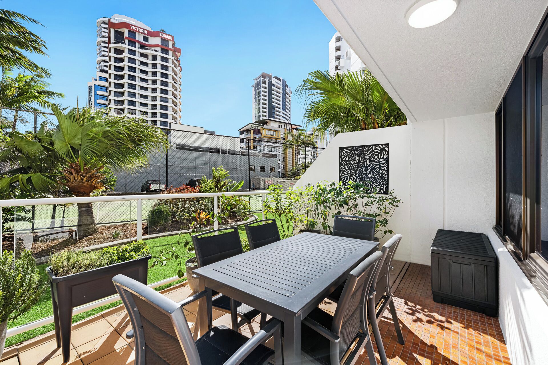 A balcony with a table and chairs, a potted plant, and a view of tall buildings.