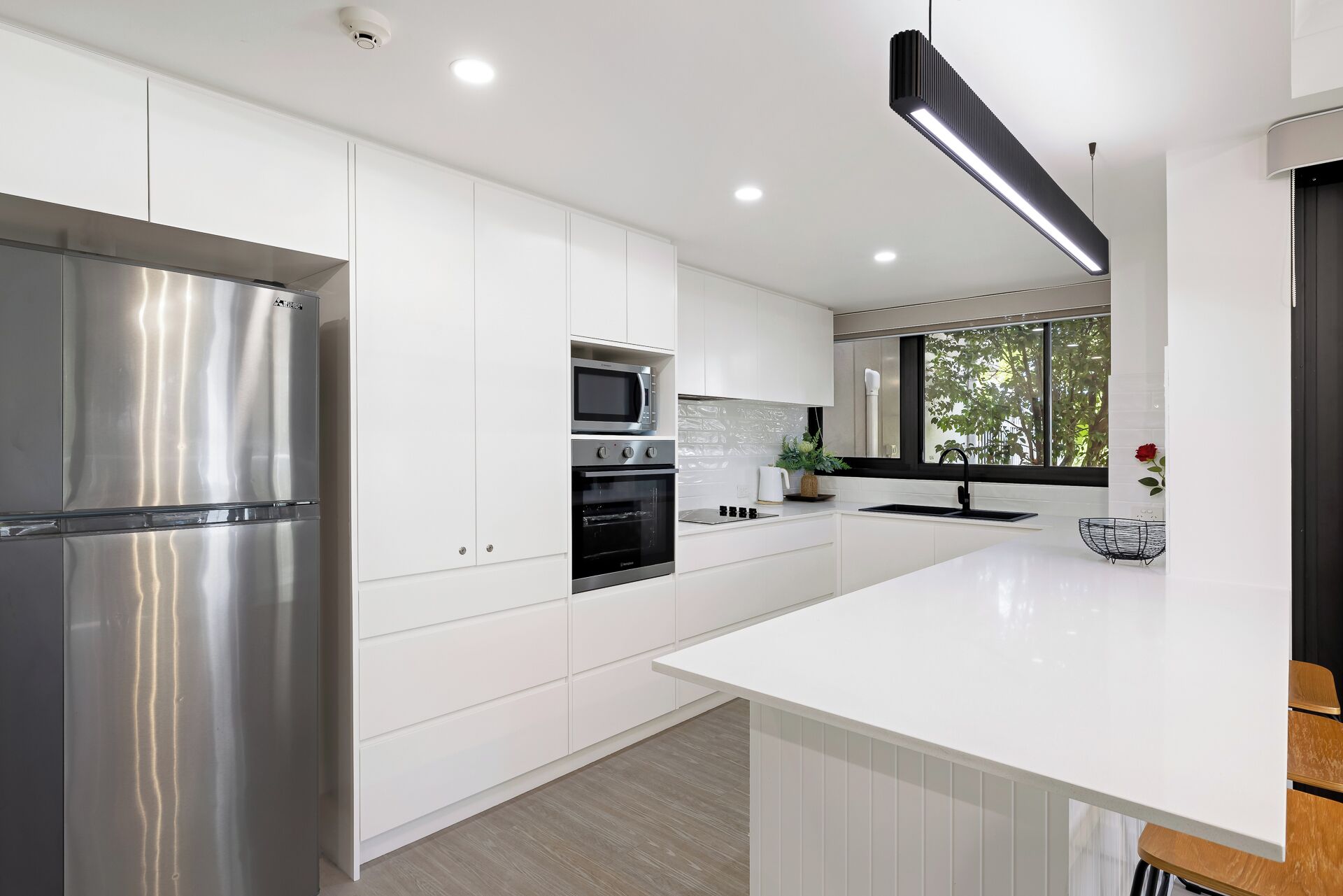 A modern kitchen with stainless steel appliances, white cabinetry, and a large island.