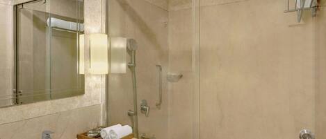 A bathroom with a glass-enclosed shower, a sink with a mirror, and a towel rack.