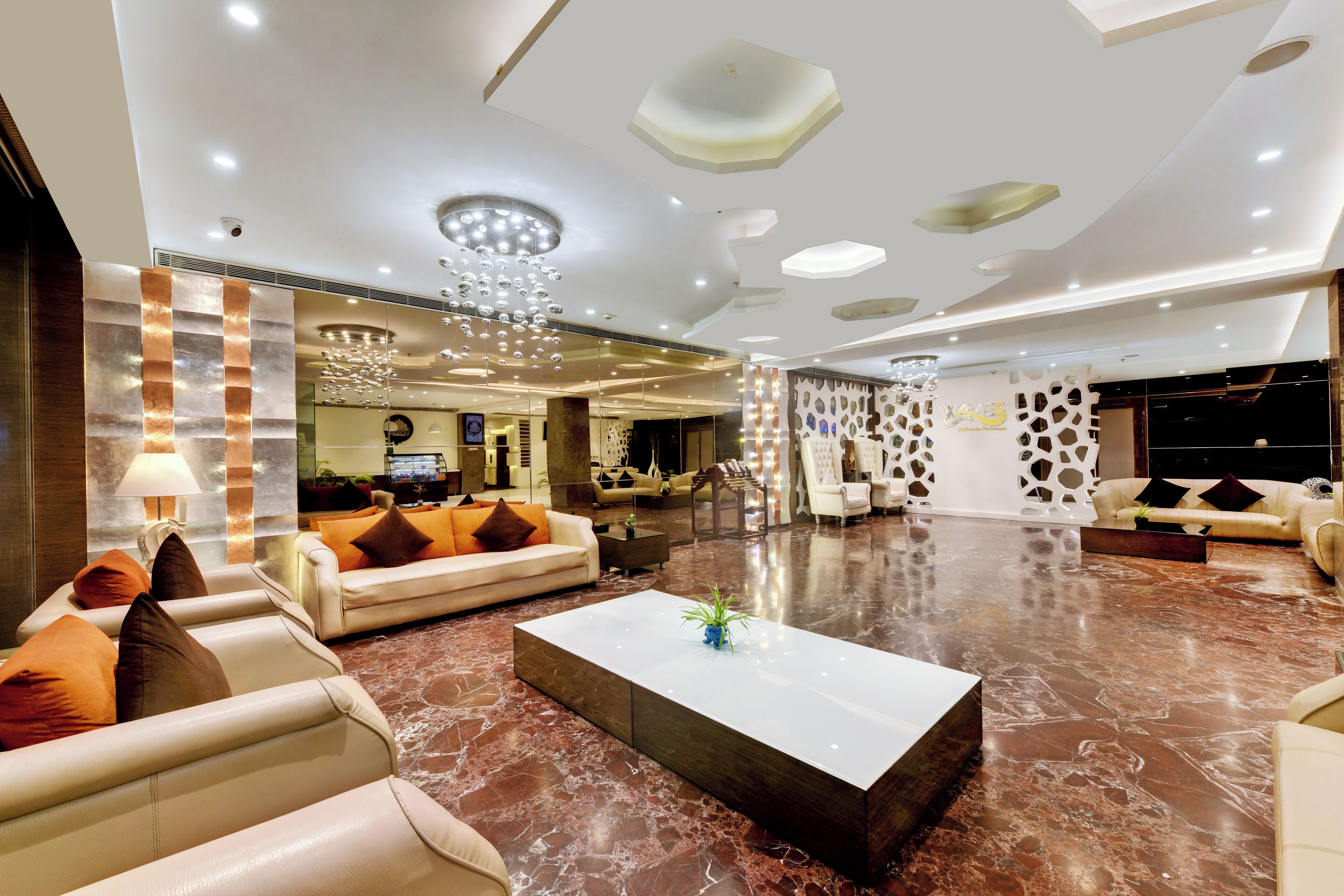 A spacious lobby with leather sofas, a marble coffee table, and a modern chandelier.