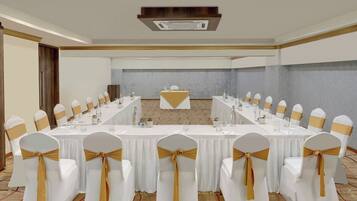 A conference room with a long table, white chairs with gold sashes, and a podium at the front.