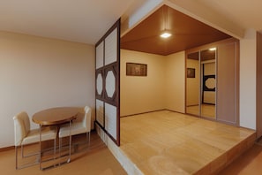 Una habitación con piso de madera, una mesa redonda con sillas y una puerta corrediza con espejo.