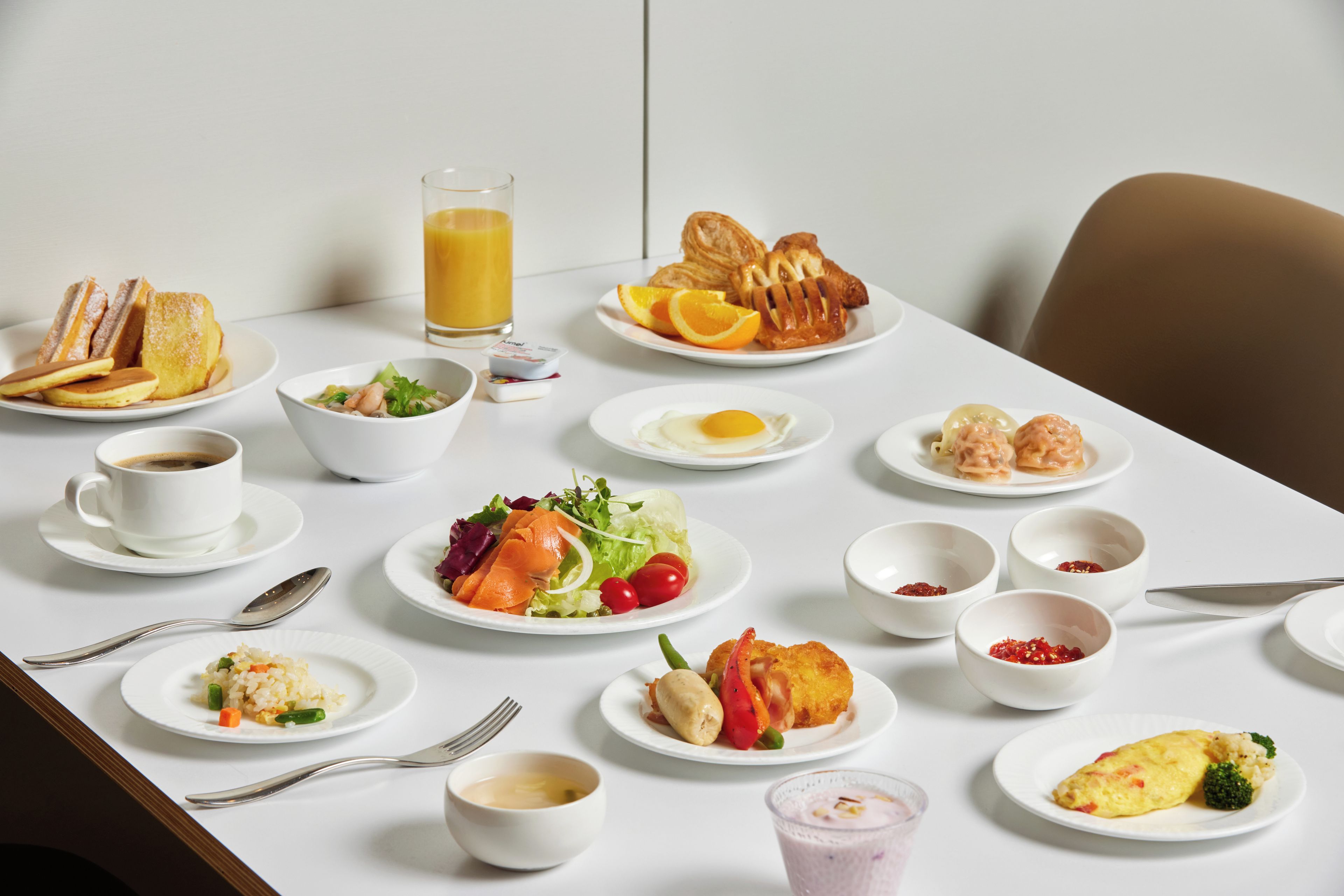 A breakfast table with various dishes including toast, pancakes, eggs, and fruit.