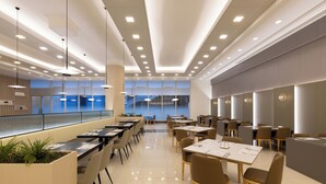 A modern dining area with long tables, chairs, and pendant lighting. - Sono Belle Byeonsan (Buan)