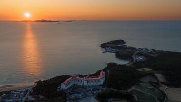 Un resort costero con un edificio grande, un puerto deportivo y vistas al mar al atardecer.