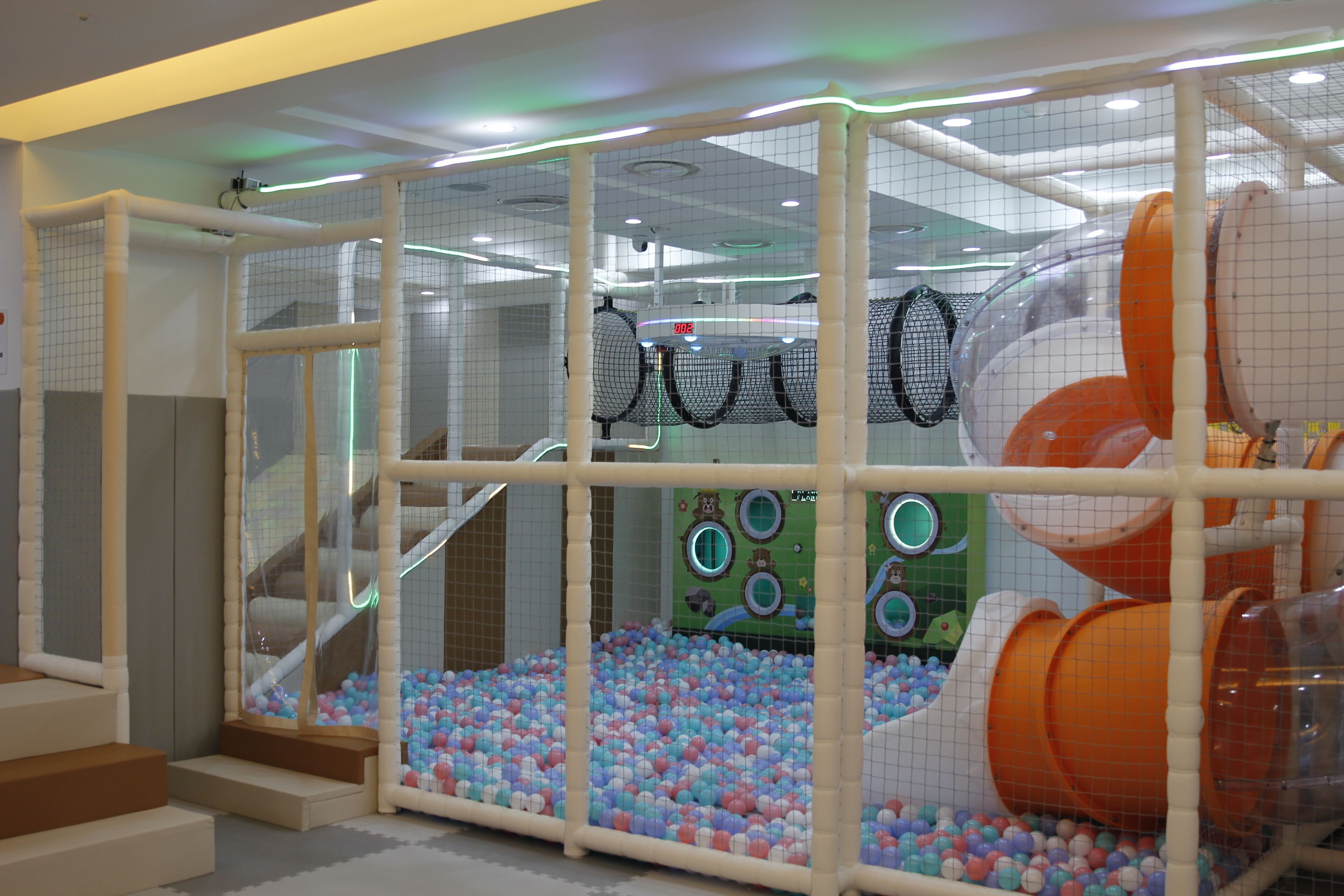 An indoor play area with a ball pit, climbing structures, and a netted play zone.