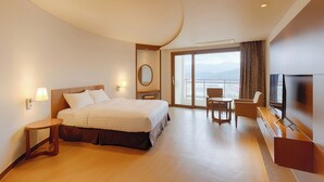A hotel room with a large bed, a desk, a chair, a TV, and a view of the city. - Sono Belle Byeonsan (Buan)