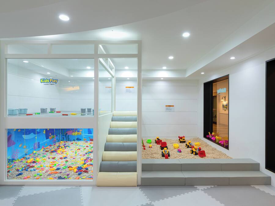 A children's play area with a colorful playroom, a staircase, and a window with toys.