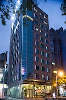 Een modern hotel met een glazen gevel, meerdere verdiepingen en een goed verlichte entree.