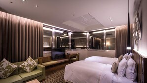 A hotel room with a bed, a sofa, a desk, a TV, and a mirror. - Green World JianPei (Taipei)