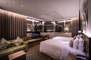 Een hotelkamer met een bed, een slaapbank, een bureau, een televisie en een spiegel.