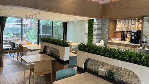 A modern cafe with indoor seating, a counter with a coffee machine, and a view of the outdoors. - Green World JianPei (Taipei)