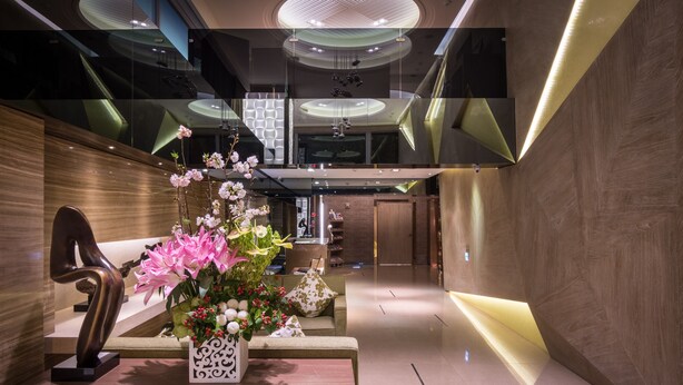 A modern lobby with a reception desk, a sculpture, and a floral arrangement. - Green World JianPei (Taipei)
