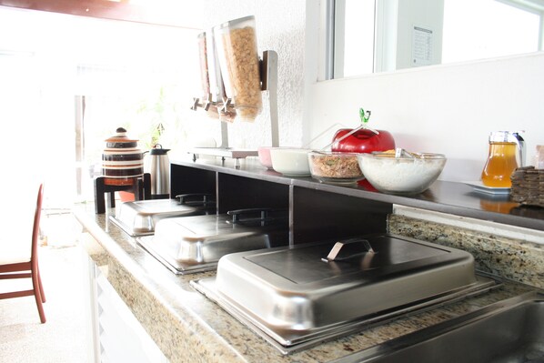 A buffet setup with various food containers and a coffee station.