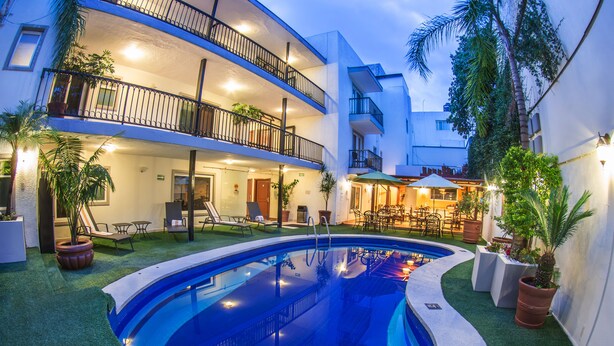 A pool area with a curved pool, lounge chairs, and a dining area with tables and chairs. - Del Marqués Hotel and Suites (Guadalajara)