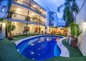 A pool area with a curved pool, lounge chairs, and a dining area with tables and chairs. - Del Marqués Hotel and Suites (Guadalajara)