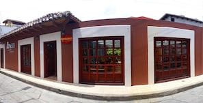Un edificio con fachada roja y blanca, grandes puertas de madera y techo de tejas.