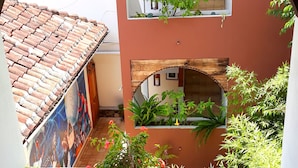 A courtyard with a tiled roof, a mural, and various plants. - Axkan Arte Hotel San Cristobal (San Cristóbal de las Casas)