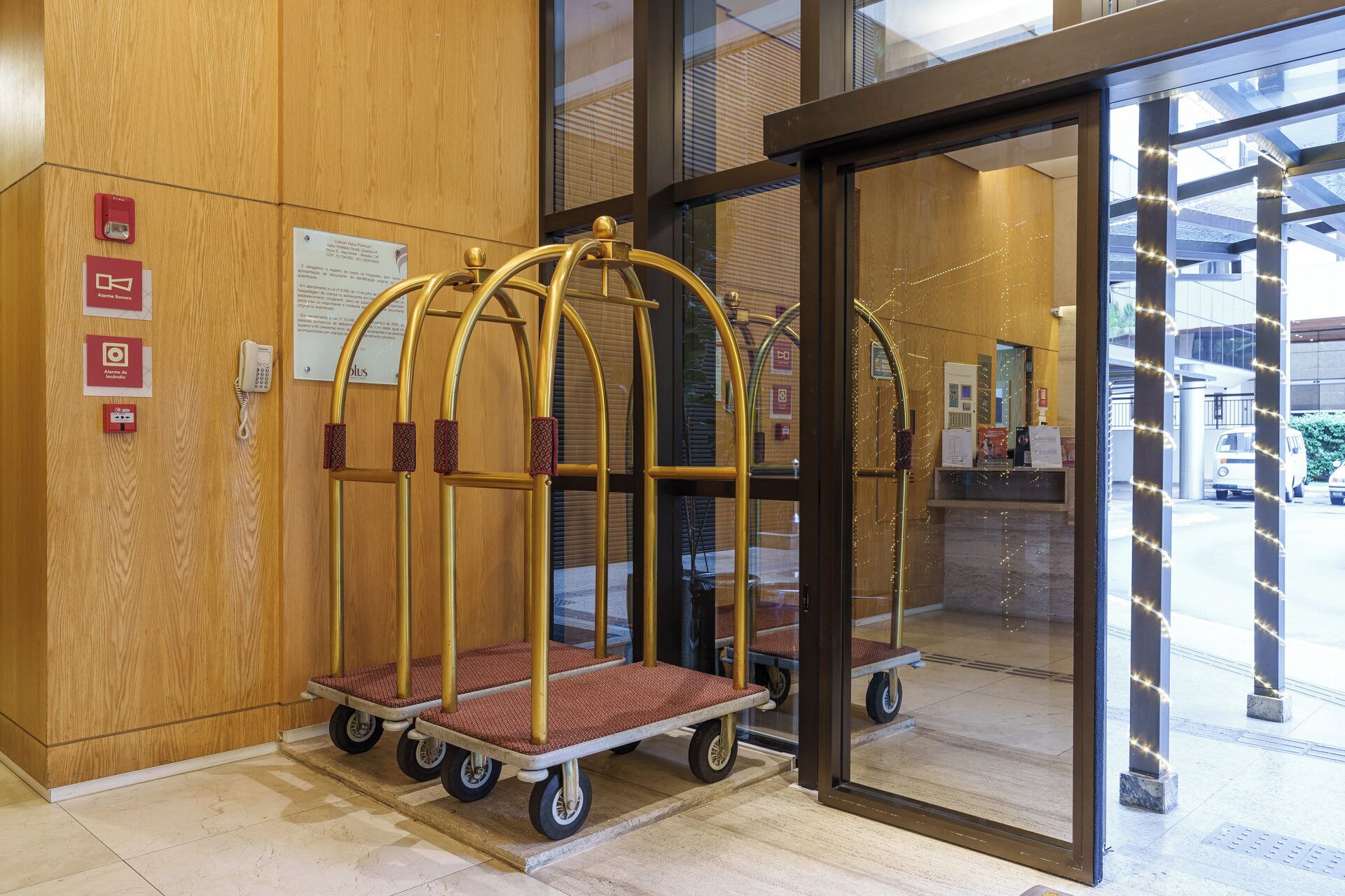 Un vestíbulo de hotel con una pared de madera, un mostrador de recepción y una puerta de vidrio que da al exterior.