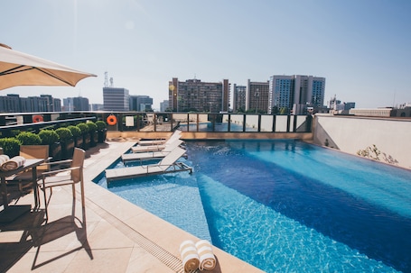 Una piscina al aire libre, sombrillas, sillones reclinables de piscina
