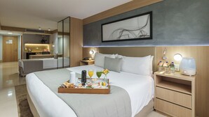 Quarto de hotel com cama, mesa de cabeceira e bandeja com itens de café da manhã.