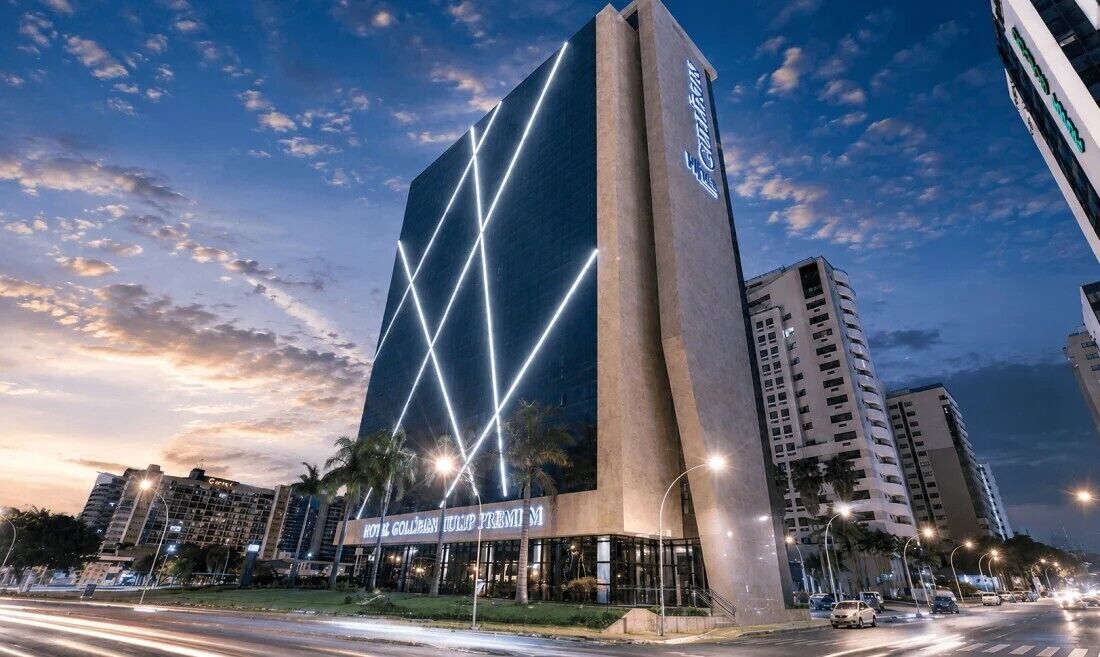 A modern hotel with a prominent vertical design, illuminated signage, and a well-lit entrance.
