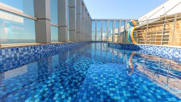 Una piscina techada, una piscina al aire libre, sombrillas