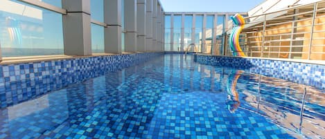 Una piscina techada, una piscina al aire libre, sombrillas