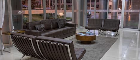 A modern lobby with a leather sofa, two armchairs, and a coffee table.
