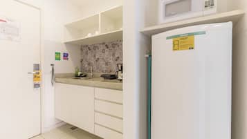 A kitchen with white cabinets, a microwave, a refrigerator, and a patterned backsplash.