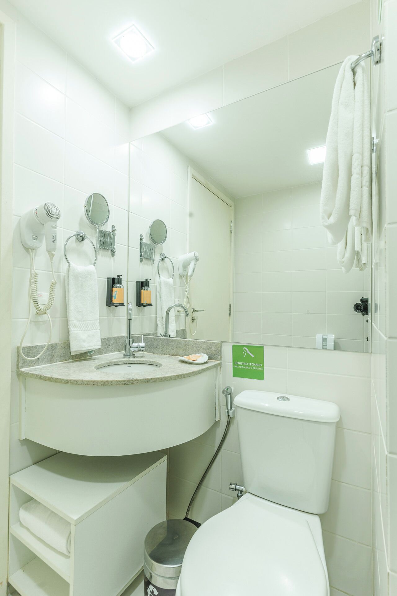 Un baño moderno con lavamanos, espejo, toallero y retrete.