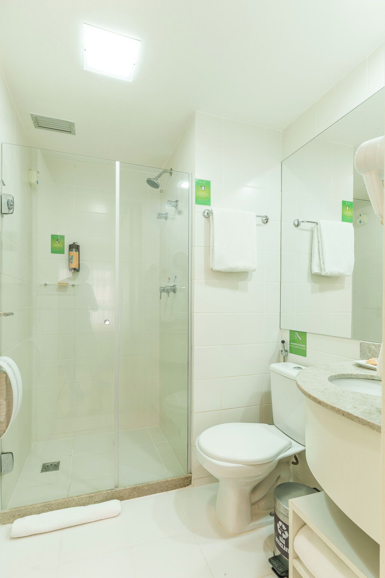 Ein modernes Badezimmer mit einer Duschkabine, einer Toilette und einem Waschbecken mit Spiegel.