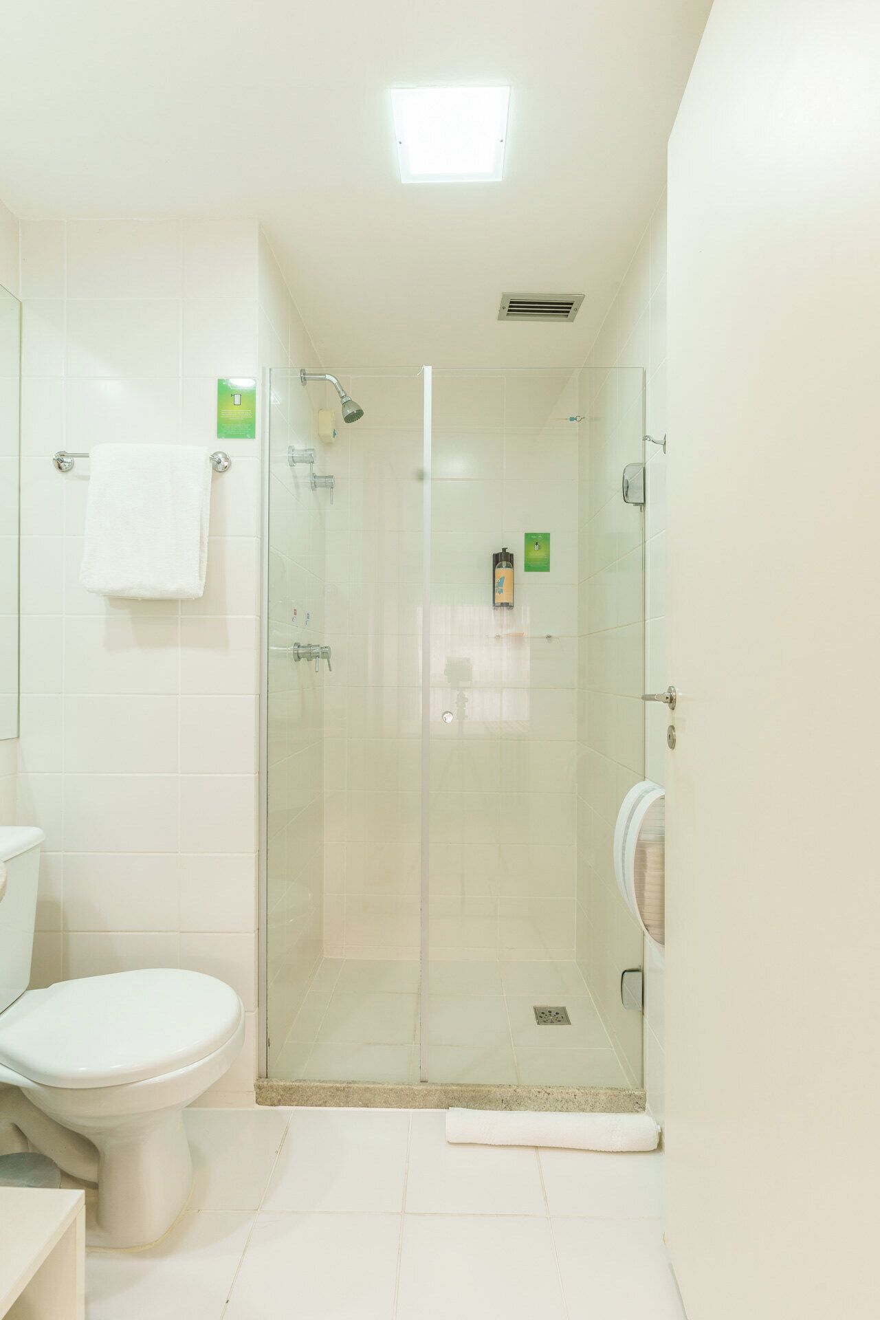 A bathroom with a toilet, a glass-enclosed shower, and a hand dryer.