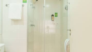 A bathroom with a toilet, a glass-enclosed shower, and a hand dryer.