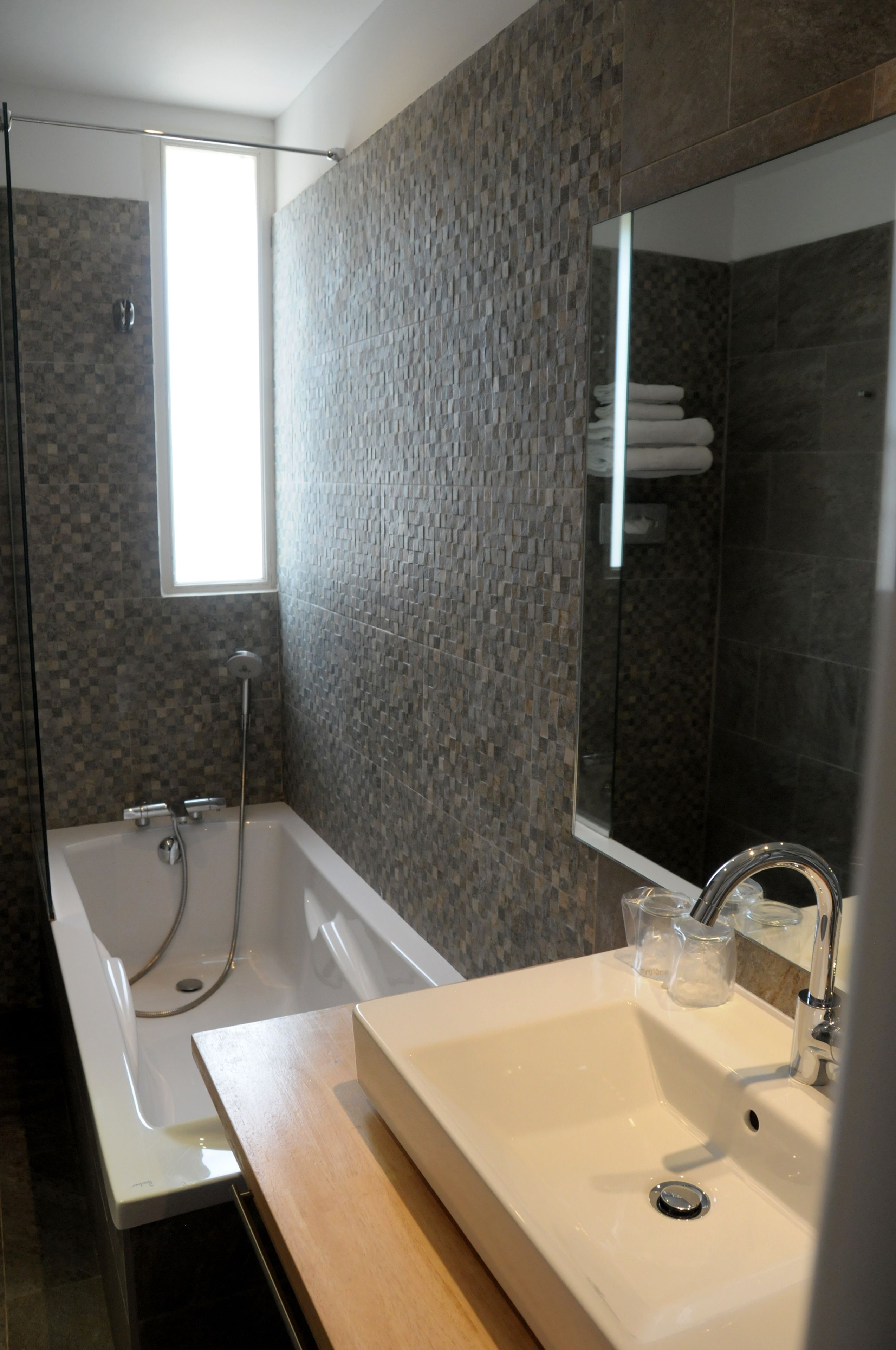 A modern bathroom with a glass-enclosed shower, a large mirror, and a white sink.
