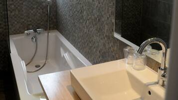 A modern bathroom with a glass-enclosed shower, a large mirror, and a white sink.