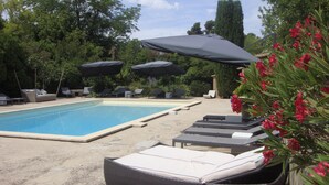 Un área de piscina con sillones de descanso y sombrillas.