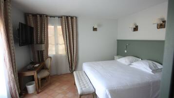 A hotel room with a bed, a desk, a chair, a television, and a window with curtains.