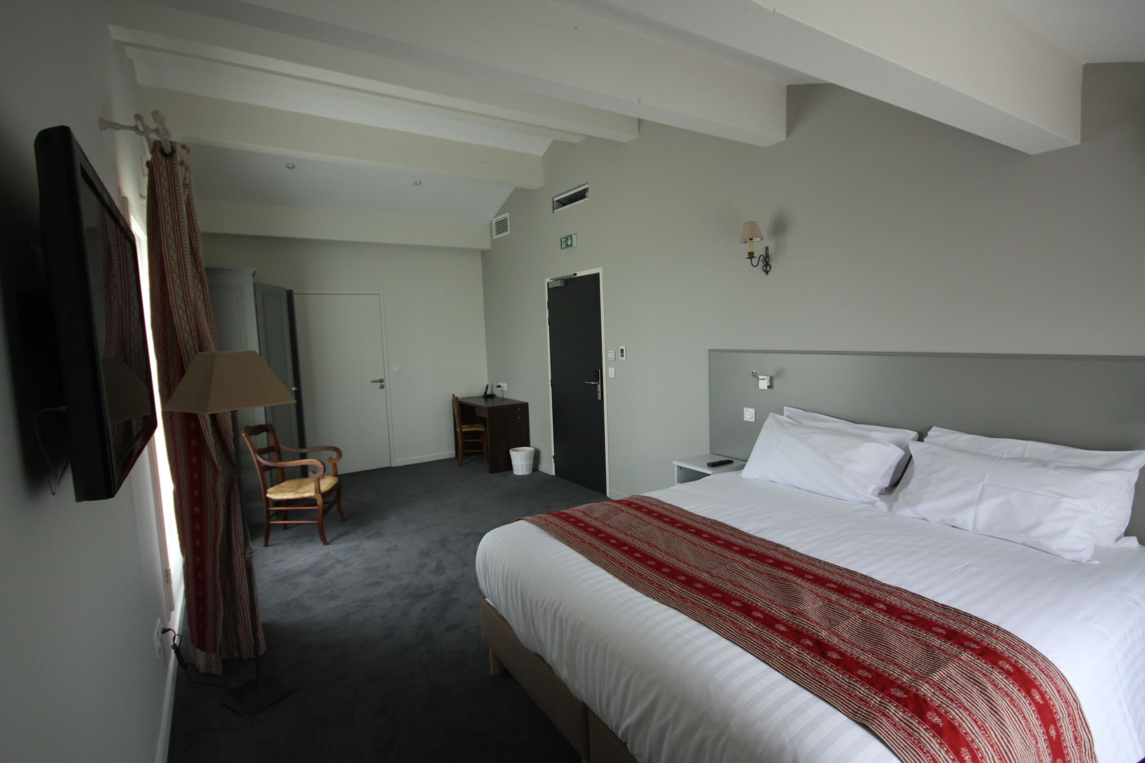 Habitació d'hotel amb un llit gran, una cadira, un escriptori i un armari.