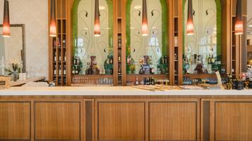 A bar area with wooden cabinets, shelves with bottles, and hanging pendant lights.