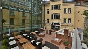 A rooftop terrace with outdoor seating, a glass conservatory, and a building with multiple windows and balconies. - Hotel Elizabeth (Trencin)